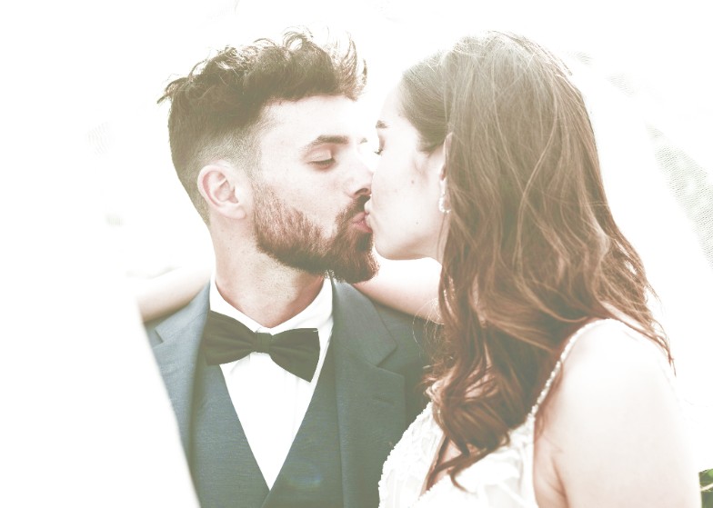 Newlywed couple kissing beneath a veil